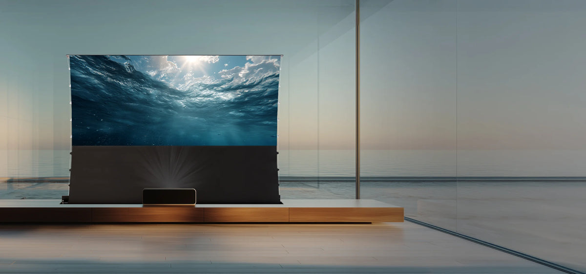 The celexon Expert floor-rising scissor screen integrated into a wooden piece of furniture, with a calm, bright living atmosphere in the background and a view of water. In front of the screen, a UST projector projects an underwater view onto the screen.