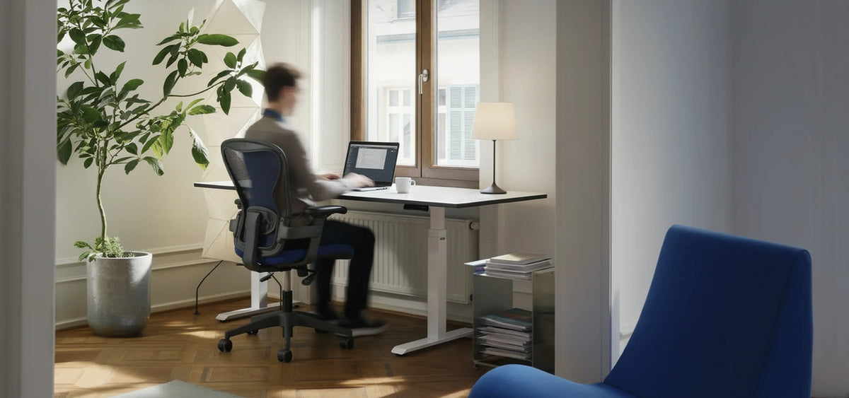A person is seated at a modern, height-adjustable celexon E-Adjust 58123 desk, working on a laptop in a bright, tidy home office. Daylight streams in through a large window.