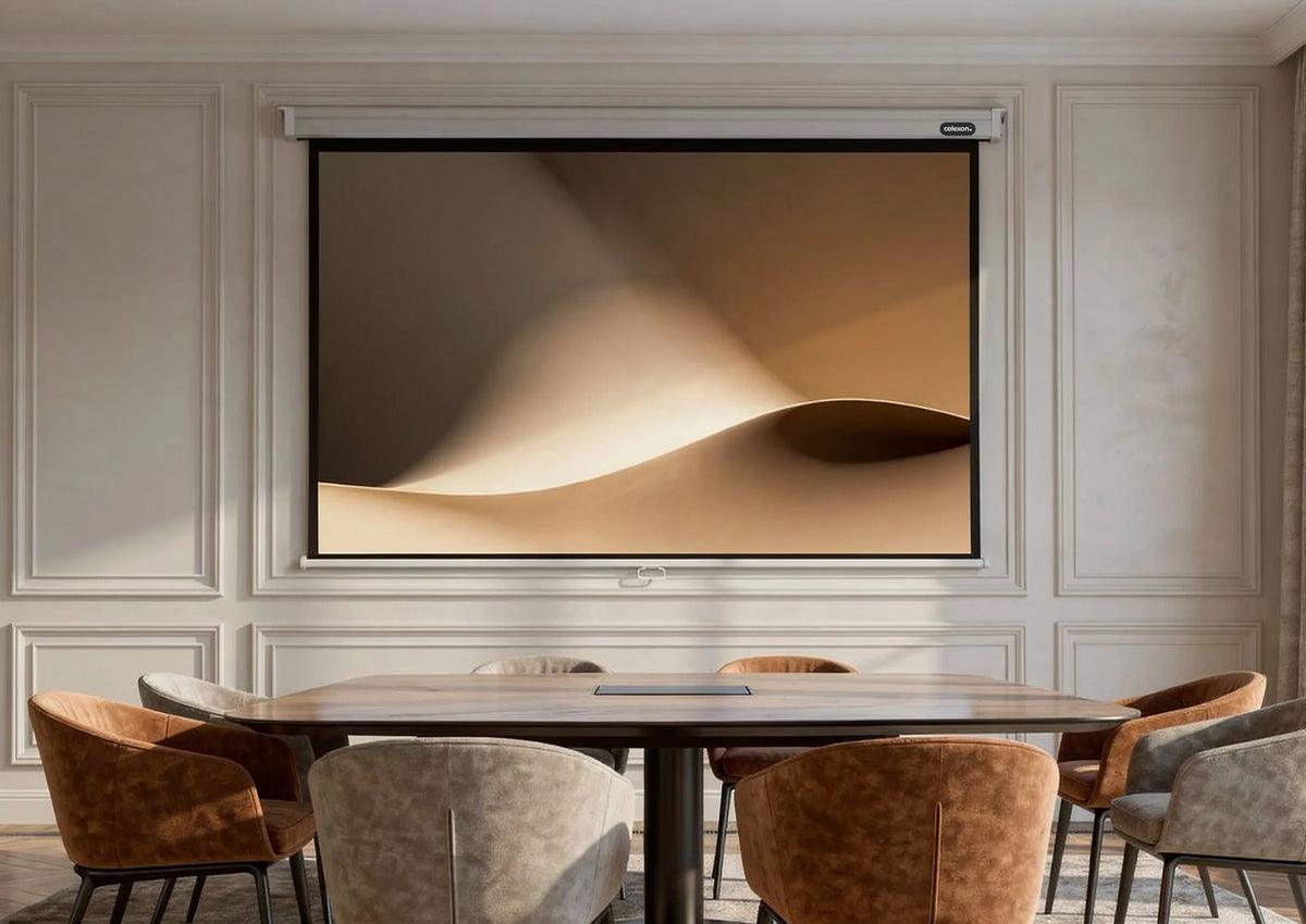 The image shows an elegant, classically furnished conference room with wall paneling, a large table, and upholstered chairs, at the center of which a celexon Manual Professional projector screen displays a calm, abstract projection of softly flowing, sand-colored shapes.