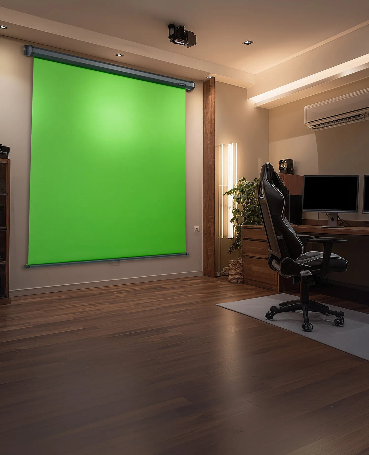 The image shows a modern studio workspace in which, on the left, a large, wall-mounted celexon manual Chroma Key green screen is installed, while on the right a tidy workstation with a wooden desk, two monitors, an office chair, a plant, and an air-conditioning unit creates a professional environment for video and content production.