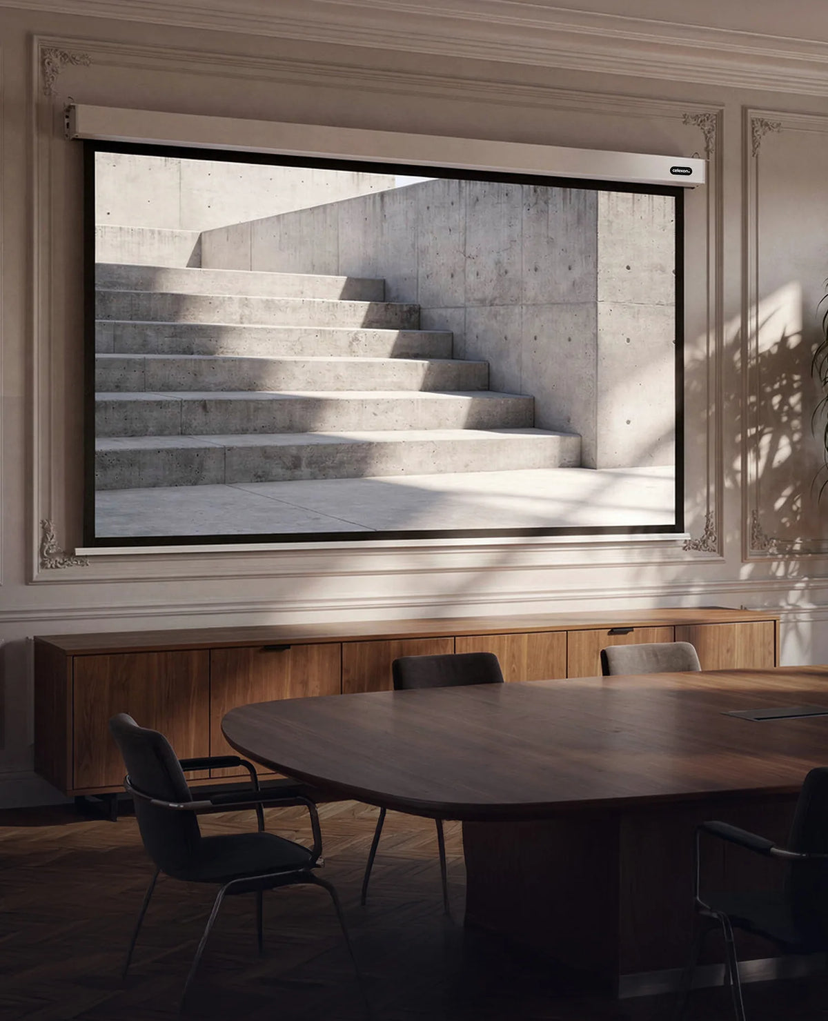 Elegant, well-lit meeting room. At the center of the scene, a large, extended celexon Professional Plus electric projection screen is mounted on the wall. Displayed on it is a minimalist architectural scene: light-colored concrete steps with clean geometric lines, intersected by natural light and striking shadows.