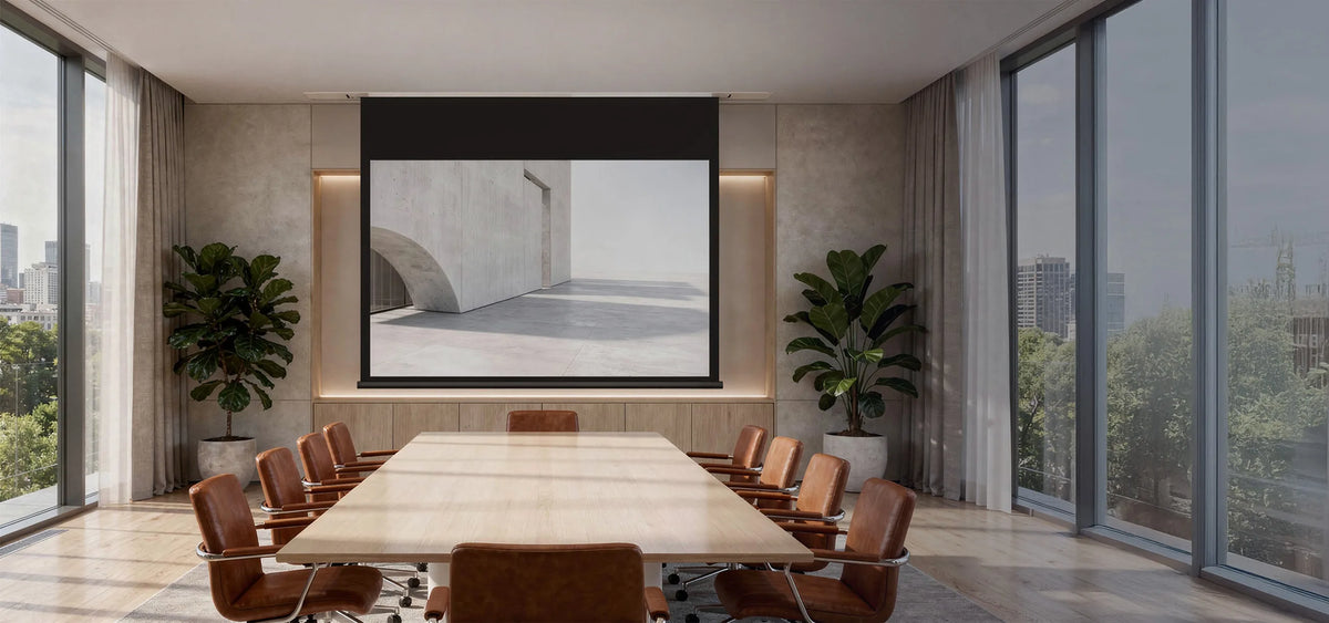 The image shows an elegant, modernly designed conference room with a large wooden table and brown leather swivel chairs, in which a celexon ceiling recessed electric projector screen Expert displays a minimalist architectural scene of light-colored concrete with clean lines and a calm, reduced atmosphere.