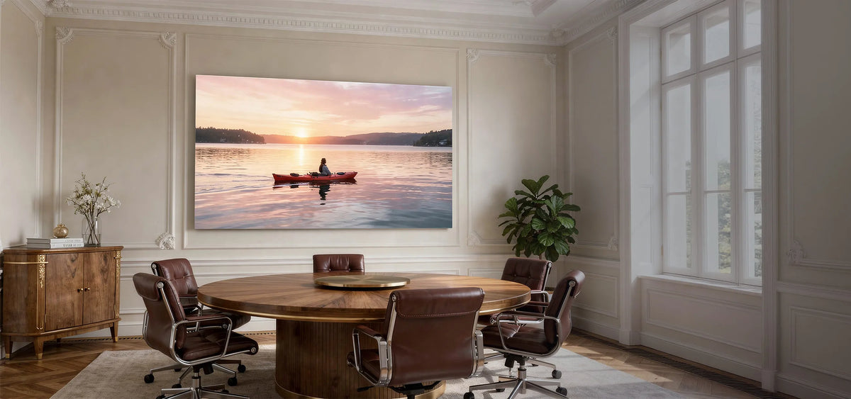 Stylish conference room featuring a celexon Expert Fixed Frame Projector Screen PureWhite, displaying a projection of a calm sunset over a lake.