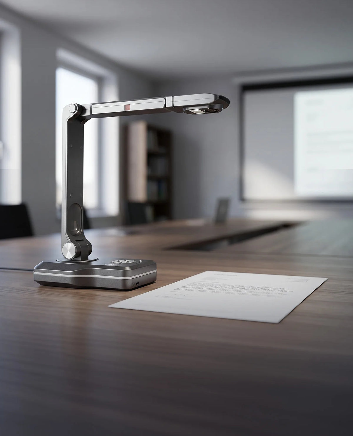 A modern celexon DK800 document camera on a conference table next to a document; in the background, a meeting room and projection screen are visible out of focus.