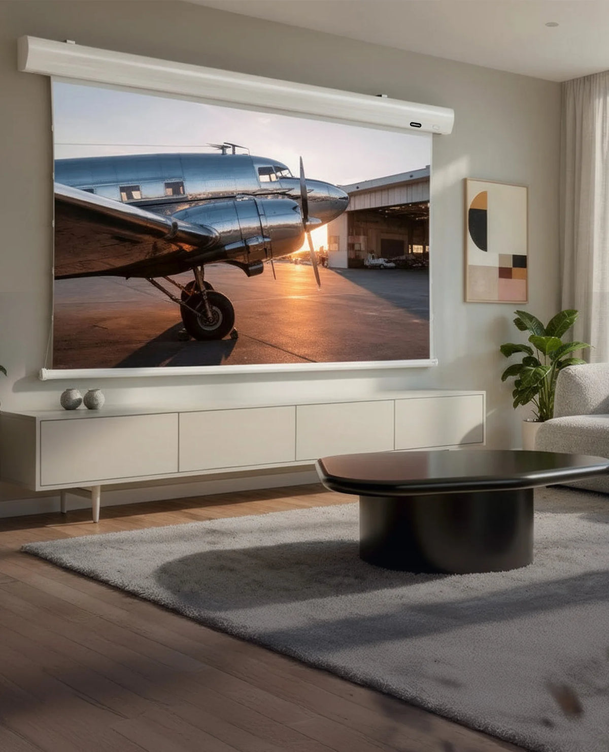 Modern, bright living room with floor-to-ceiling windows and a city view, featuring an elegant celexon HomeCinema High Contrast Frame Projector Screen – Dynamic Slate ALR displaying an atmospheric projection of a nostalgic propeller aircraft in warm sunlight.